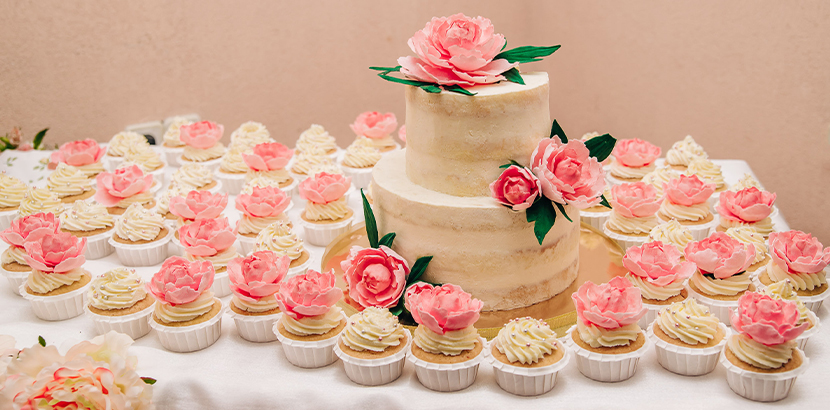 Kleine Hochzeitstorte und passende Cupcakes im Vintage-Stil.
