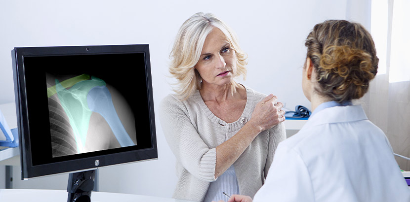 Medizinische Beratung bei der die Orthopädin die Daten eine Schulter-Röntgen bespricht.